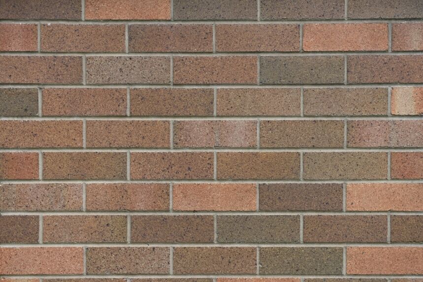 A close-up view of the brick wall showcases architectural elegance with its Architectural Dark Cream bricks, arranged meticulously in a horizontal pattern and exhibiting various shades of brown. The speckled textures add a rustic, weathered charm to the composition.
