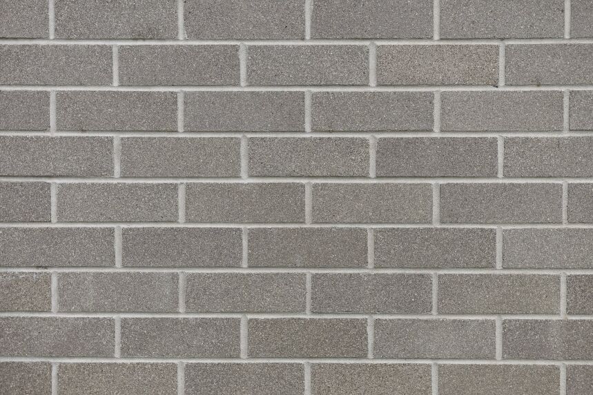 A detailed look at the Architectural Light Silver Grey Face features a grey brick wall with a smooth, uniform pattern and consistent spacing between the bricks. The texture is slightly coarse, and the wall's neutral silver-grey tones are highlighted by architectural lighting.