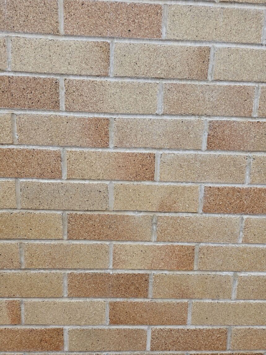 The image showcases a wall constructed with Architectural Light Medium Cream bricks, featuring a staggered layout of light brown and medium cream tones. The visible mortar lines and textured surface lend a rustic and classic look to the design.