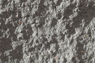 A detailed close-up of the ArrinaStone Oyster surface reveals its rough, textured appearance with distinct irregular patterns and subtle indentations. The gray hue shows slight variations throughout, emphasizing the material's rugged nature.