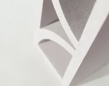 Close-up of GB Breeze Blocks Arc Pottery, a modern abstract geometric white sculpture with curved and angled edges, casting soft shadows on a light background.