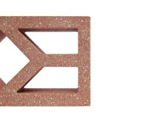A close-up of the GB Breeze Blocks Diamond Pottery in red-brown shows its geometric cut-out design, inspired by pottery. Set against a white background, only part of the block appears on the left, highlighting its unique style.