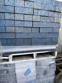 A pallet holds neatly stacked Laguna Glazed Bricks in blue, partly wrapped in plastic. The Littlehampton Bricks and Pavers logo appears on a label, while some bricks are splattered with a darker blue shade.
