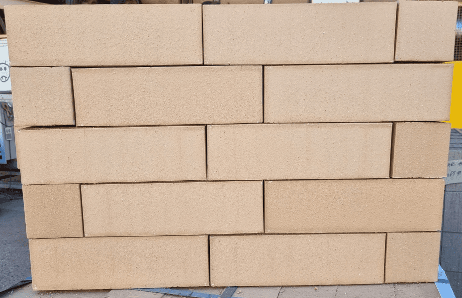 A stack of evenly arranged, rectangular Modular Cream bricks creates a neat, interlocking pattern. The bricks are uniformly colored and stacked on a flat surface.