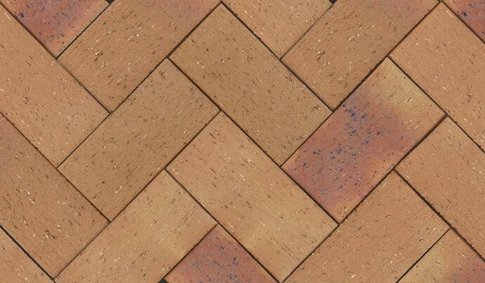 The Classic Lasseter Gold features a detailed view of a herringbone paver pattern, showcasing rectangular pavers in reddish-brown and tan shades with dark speckles. The pavers are arranged diagonally to create a distinct gold-toned zigzag design.